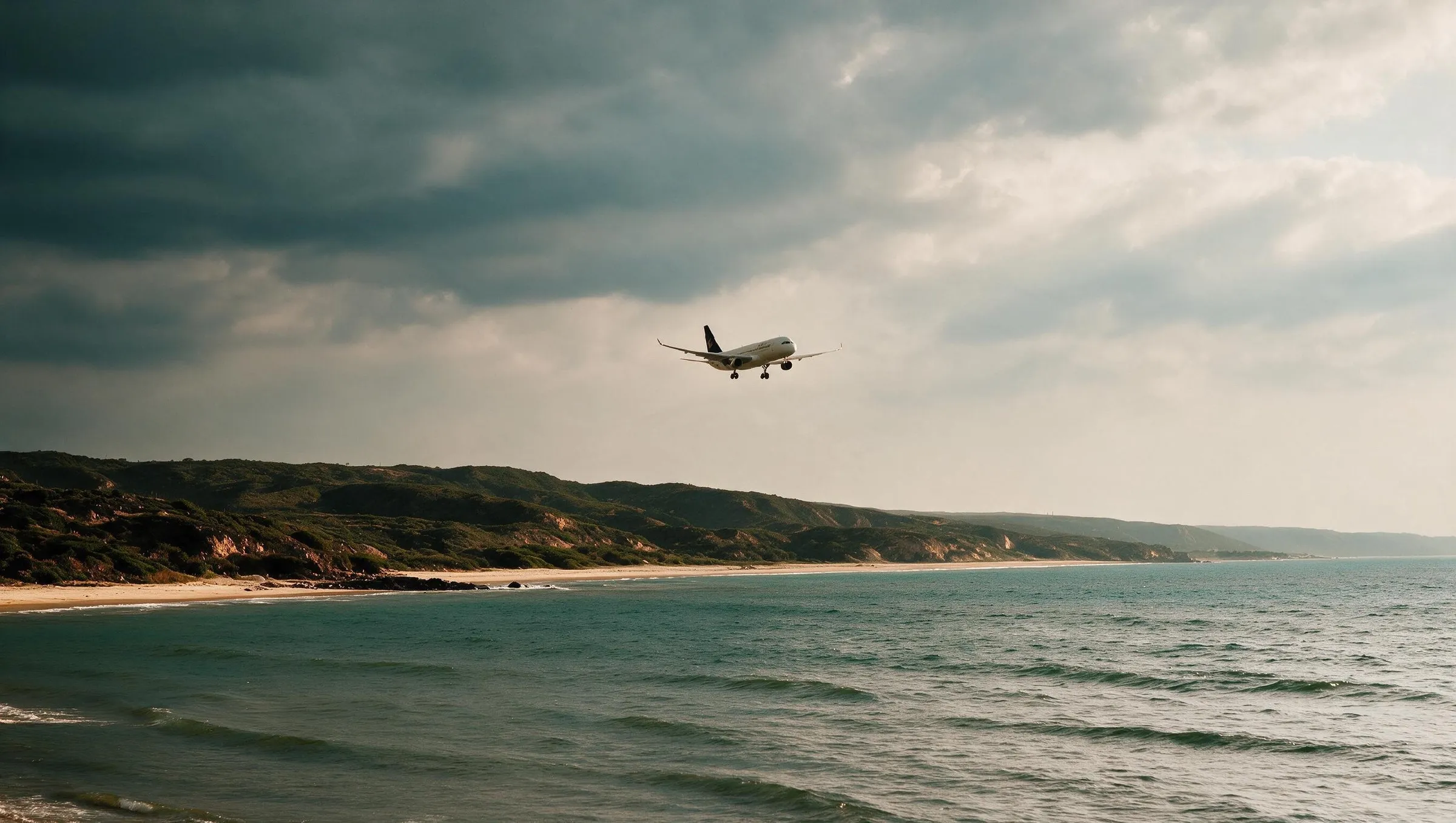An aircraft on approach over the coastline under heavy monsoon cloud