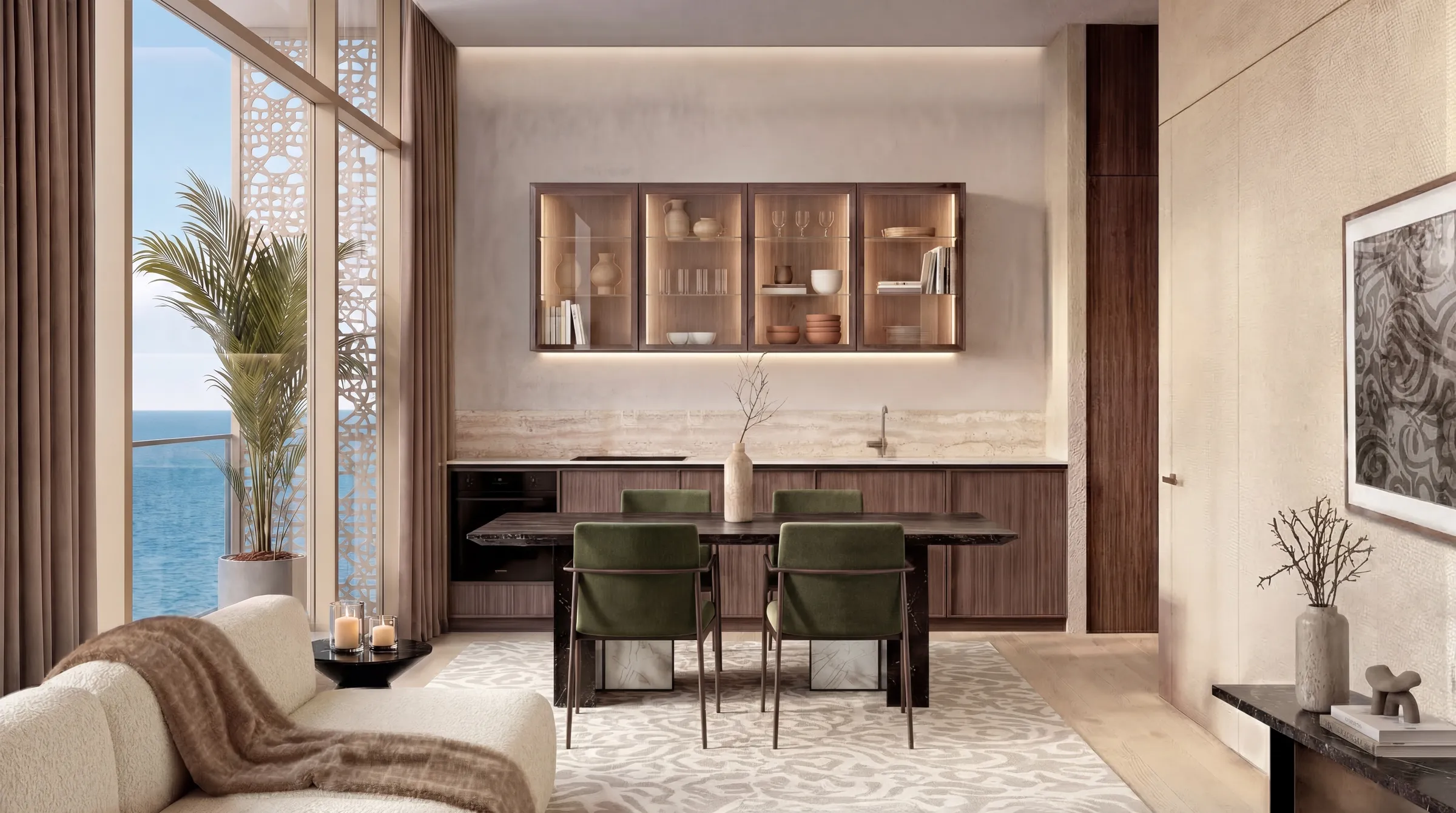 Open kitchen and dining area with a dark stone table, green upholstered chairs and lit glass-fronted wall cabinets